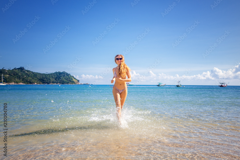 Attractive young woman with long blond hair running down the beach, relaxing and vacation in the seaside resort