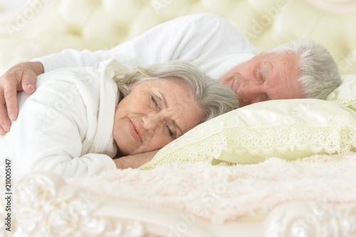 happy senior couple sleeping in bed 