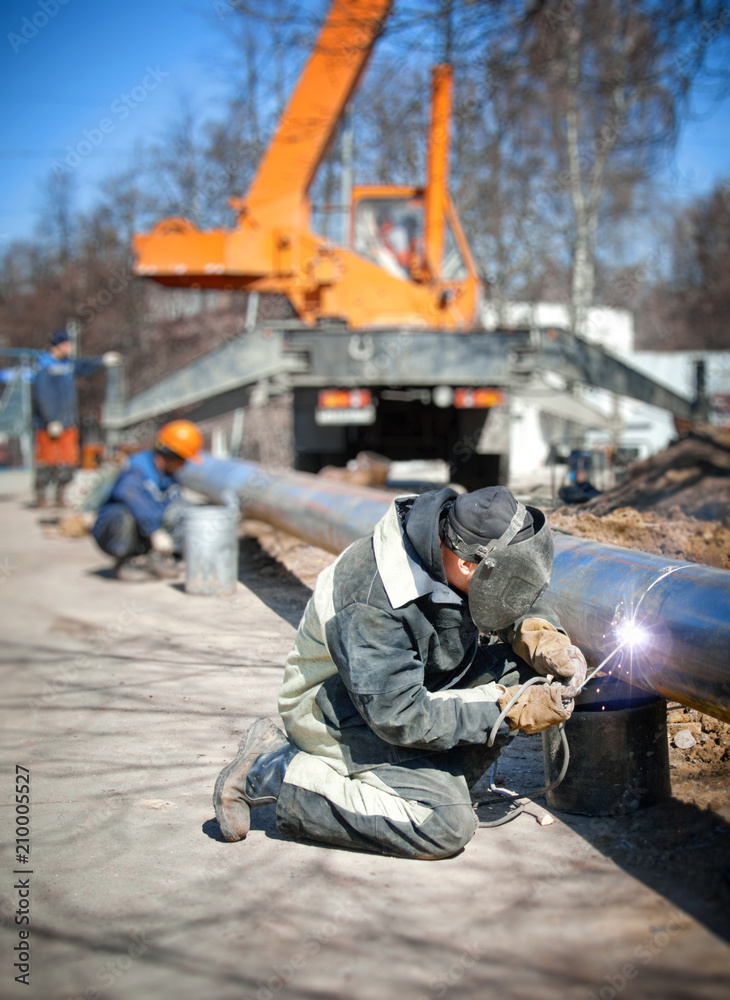 Welder welding pipe on background of the construction site Welder welding pipe on background of the construction site
