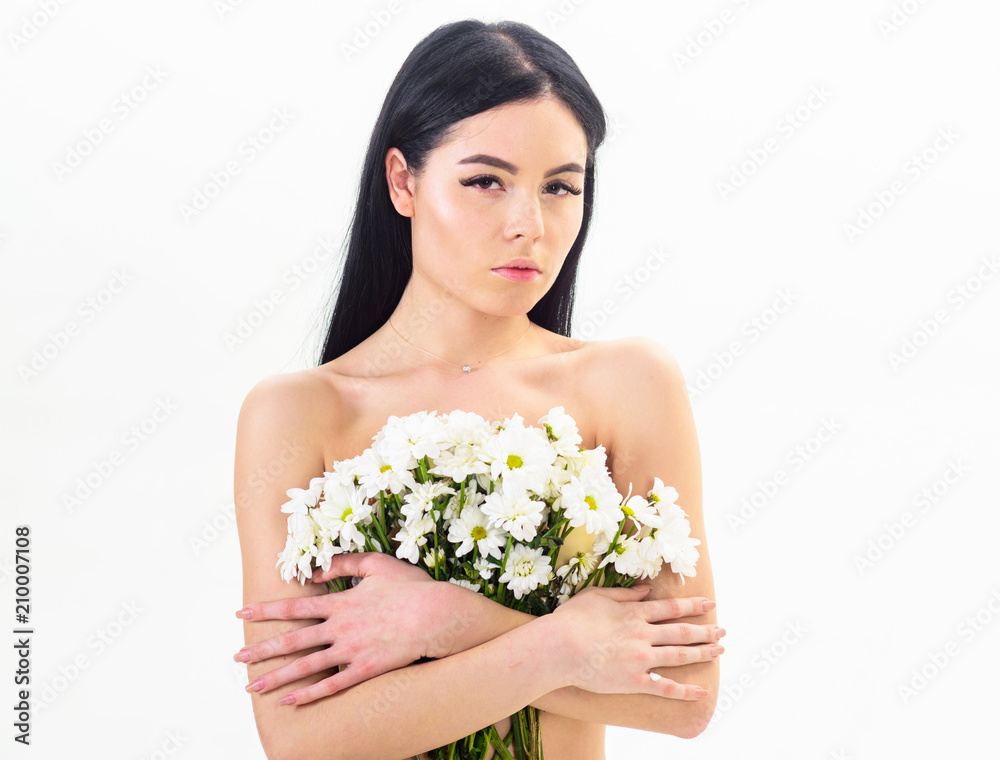 Woman with smooth healthy skin looks attractive. Lady covers breasts with flowers, isolated on white. Natural cosmetics concept. Girl on calm face naked holds chamomile flowers in front of breasts. Woman with smooth healthy skin looks attractive. Lady covers breasts with flowers, isolated on white. Natural cosmetics concept. Girl on calm face naked holds chamomile flowers in front of breasts.