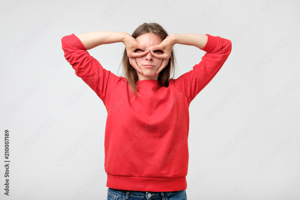 Fototapeta premium Pretty girl holding fingers near eyes like glasses: mask like super hero