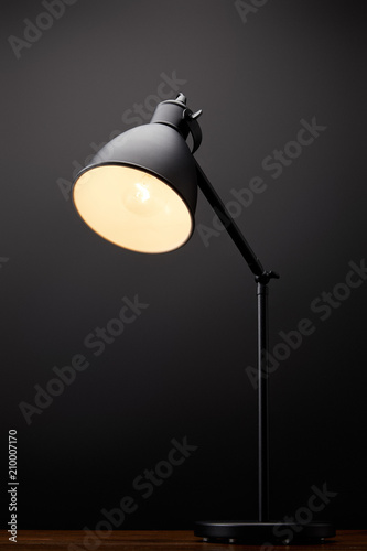 close up view of black lamp on wooden tabletop on black background