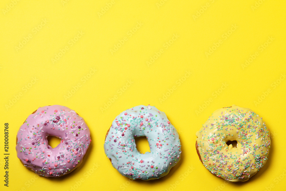 Three glazed donuts on a yellow background