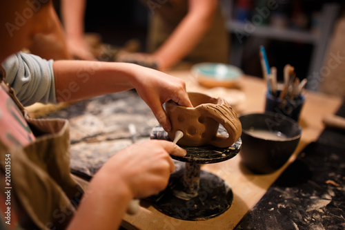 Child girl making a cup from red clay at pottery workshop