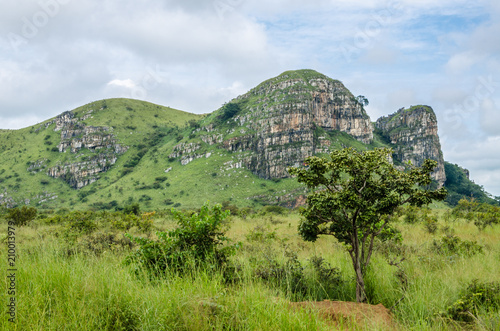 Rocky green mountain range with lush grass in foreground in landscape in northern Angola, Africa