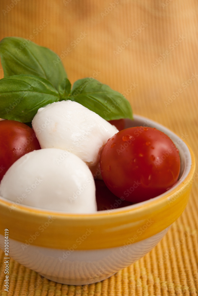 Bowl with little mozzarella tomatoes and fresh leaves of basil Bowl with little mozzarella tomatoes and fresh leaves of basil