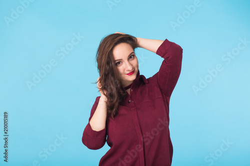 Beautiful smiling woman with clean skin, natural make-up, and red lips on blue background with copy space