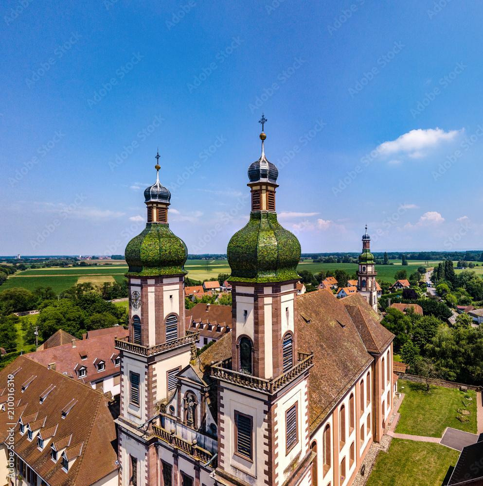Soaring majestic church Saint Maurice in little french village Ebersmunster. Aerial drone view.