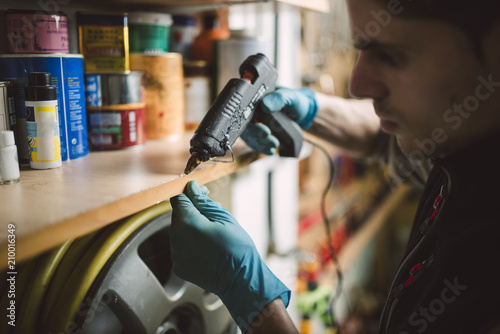 Man using a hot glue gun on shelf in workshop photo