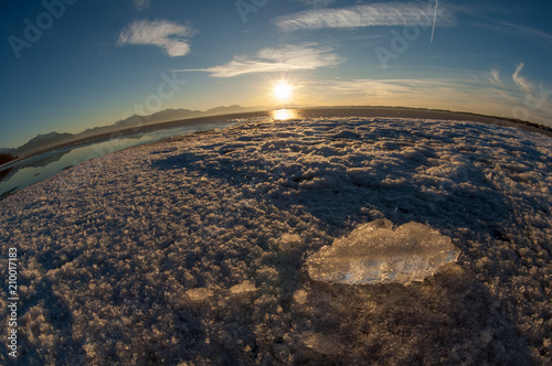 Floe of frozen lake chiemsee with alpine mountains in background