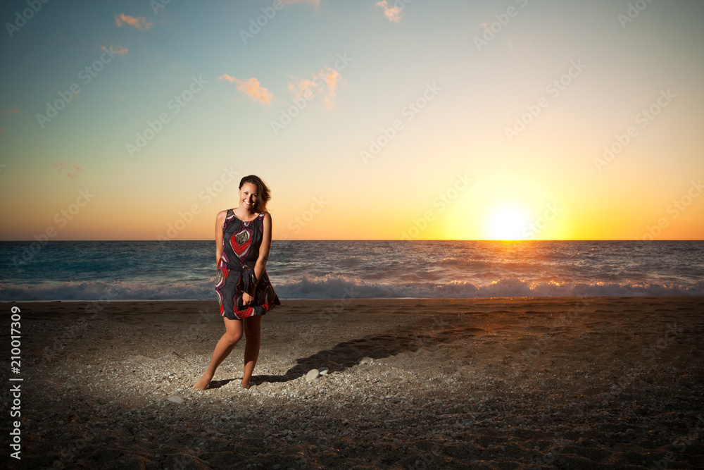 Young woman standing on the beach on sunset