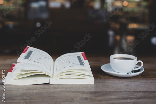 Open book with cup of coffee on wooden table