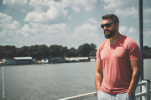 Bearded macho man standing by the river