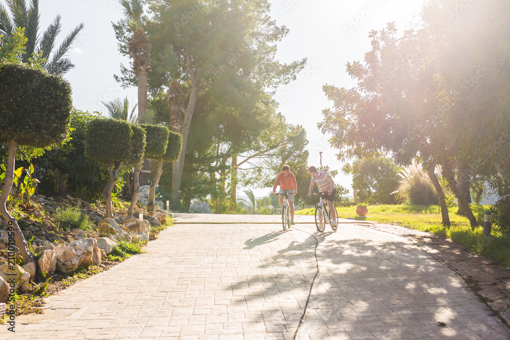 Obraz premium Two cyclists with bicycles at sunset in park