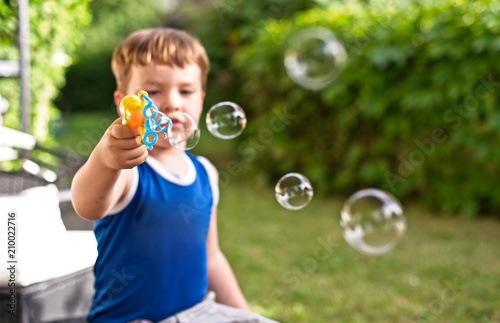 Little boy is blowing soap bubbles. Outdoors