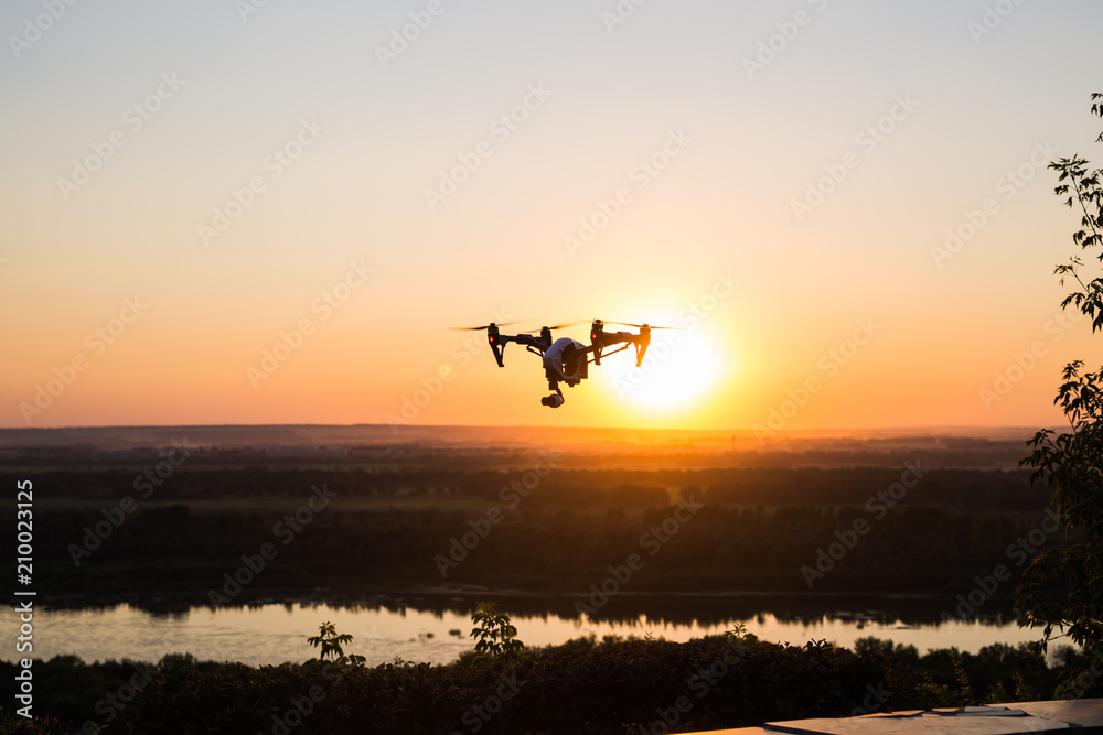 silhouette of drone, quadrocopter with photo camera flying in the sky.