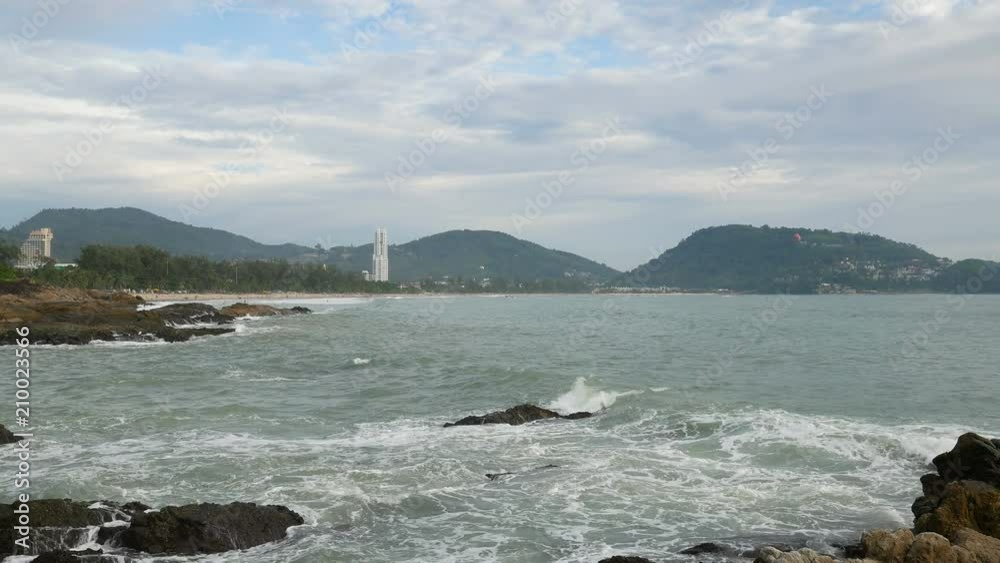 sea wave hit the rock shore seascape , Patong sand beach Phuket parasail , tree and mountain are background , sea wave hit the rock shore seascape , Patong sand beach Phuket parasail , tree and mountain are background ,