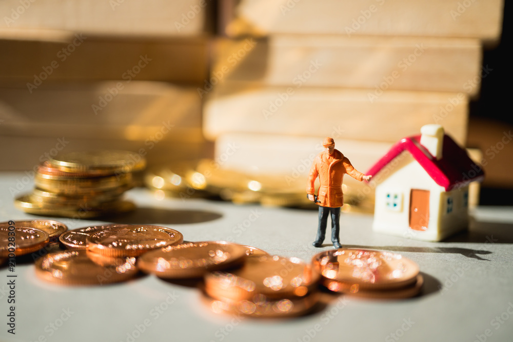 Miniature people, engineer standing with stack coins and mini house using as business, industry and financial concept Miniature people, engineer standing with stack coins and mini house using as business, industry and financial concept