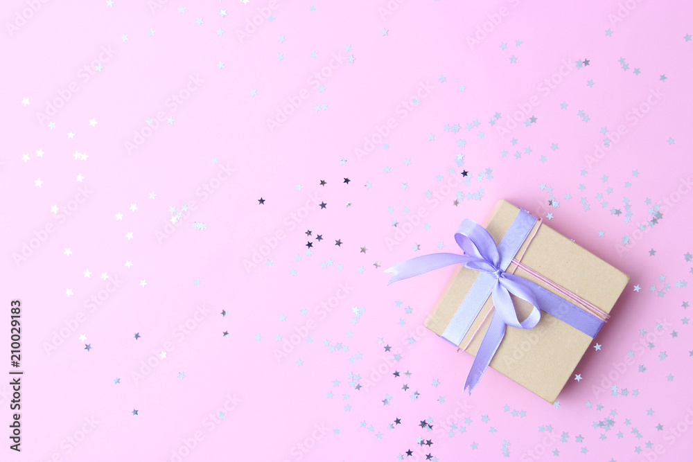gift and sparkles of confetti on a colored background top view. minimalism, insta. flatlay 