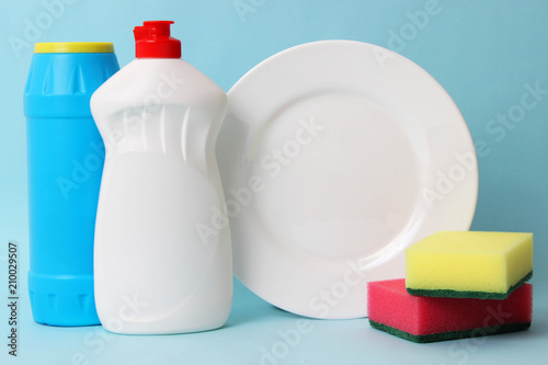 dishwashing liquid, sponges, plate on a colored background. household chores, washing dishes