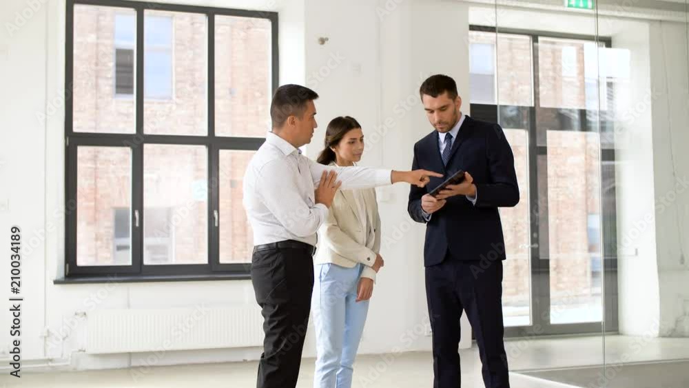 real estate business, sale and people concept - realtor showing tablet pc computer to customers at new office room real estate business, sale and people concept - realtor showing tablet pc computer to customers at new office room