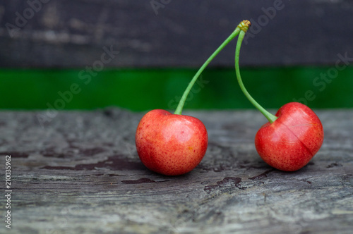 Fresh two sweet cherries on a wooden bench background. fresh ripe cherries. 2 cherries in the open air on the background