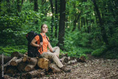 girl tourist with a backpack relax in the woods on logs