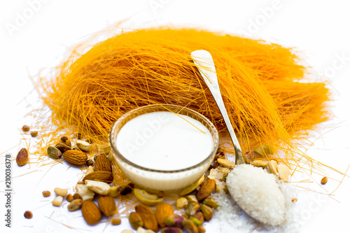 Close up of Raw vermicelli or sevee or seviyan or seviyaan and dry fruits isolated on white with a bowl of milk used to make kheer. photo