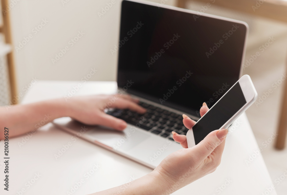 Female office worker using mobile and laptop with blank screen Female office worker using mobile and laptop with blank screen