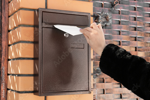 Woman putting letter in mailbox outdoors photo
