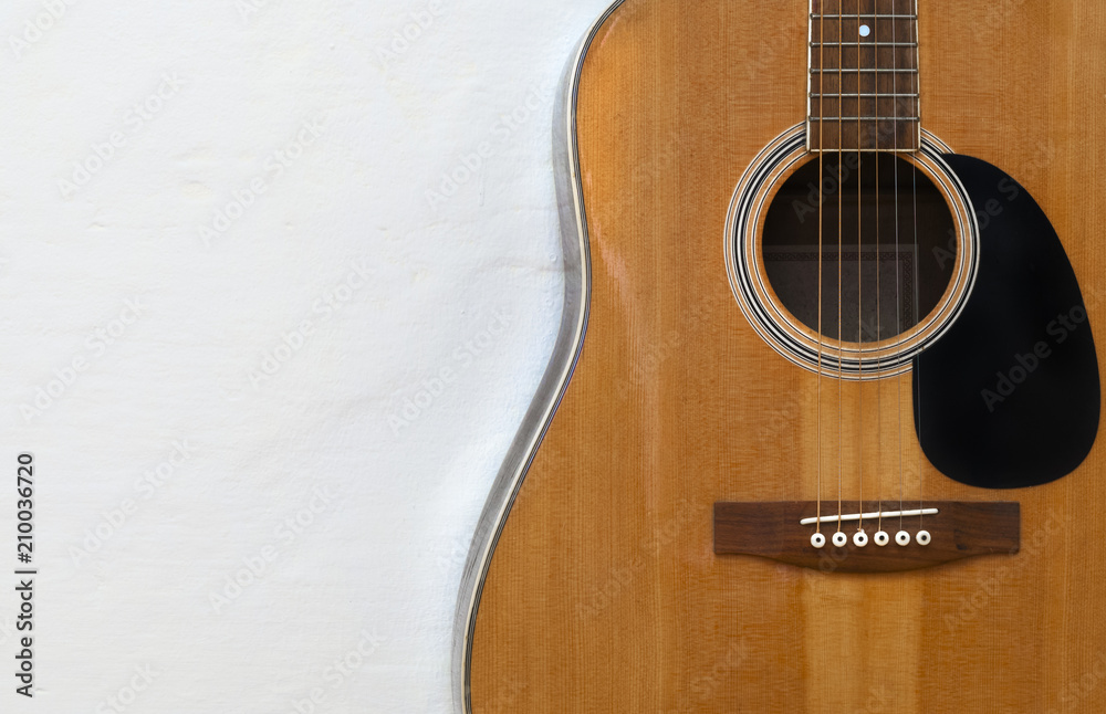 Fototapeta premium Acoustic guitar on a textured white wall