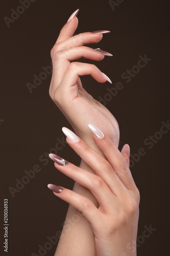 Beautiful classic manicure with crystals on female hand. Close-up. Picture taken in the studio