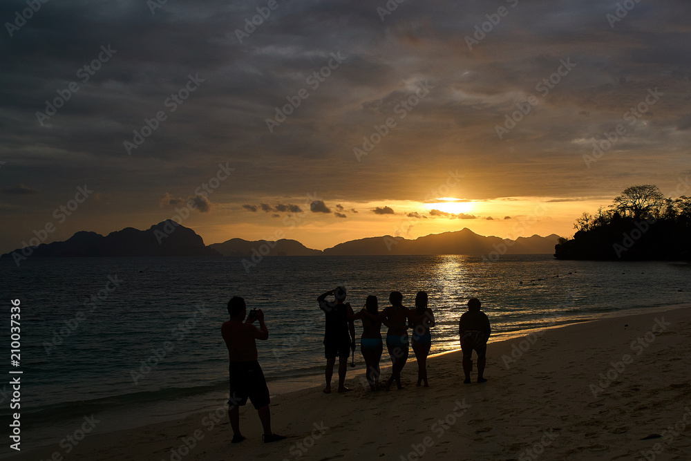 Fototapeta premium Silhouette of a couple walking on the beach at sunset in El Nido, Palawan, Philippines