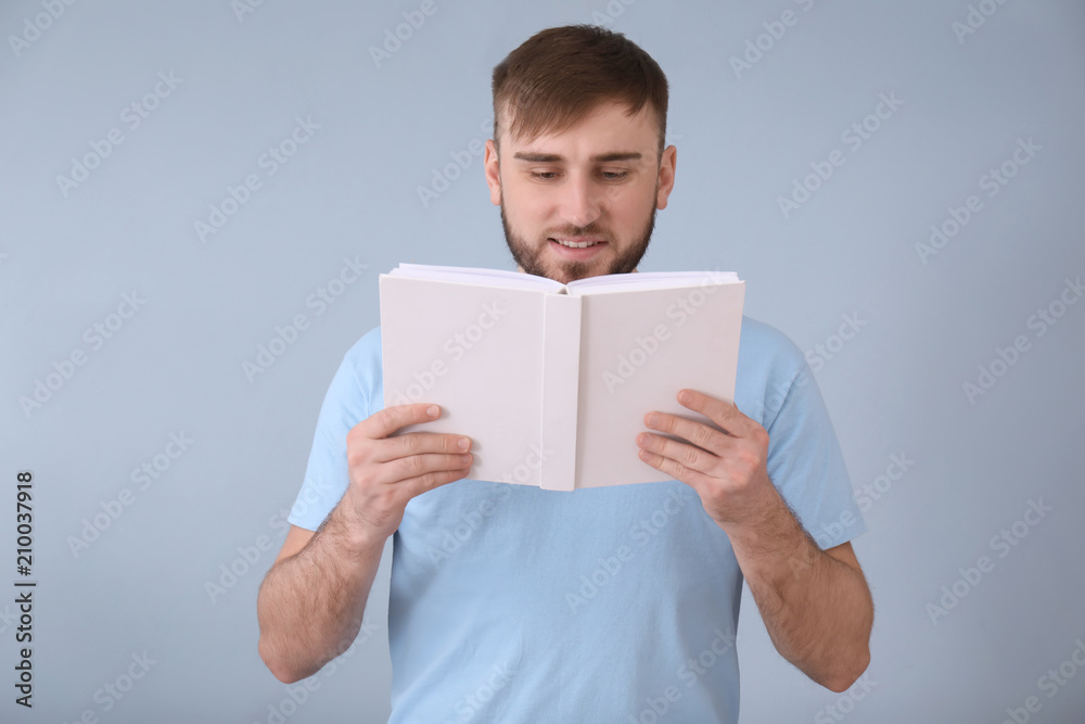 Young man reading book on color background Young man reading book on color background