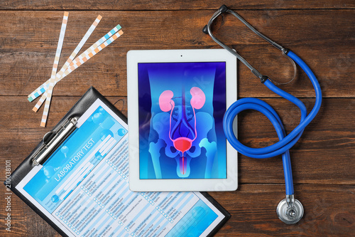 Flat lay composition with tablet, stethoscope and test form on wooden background. Urology concept photo