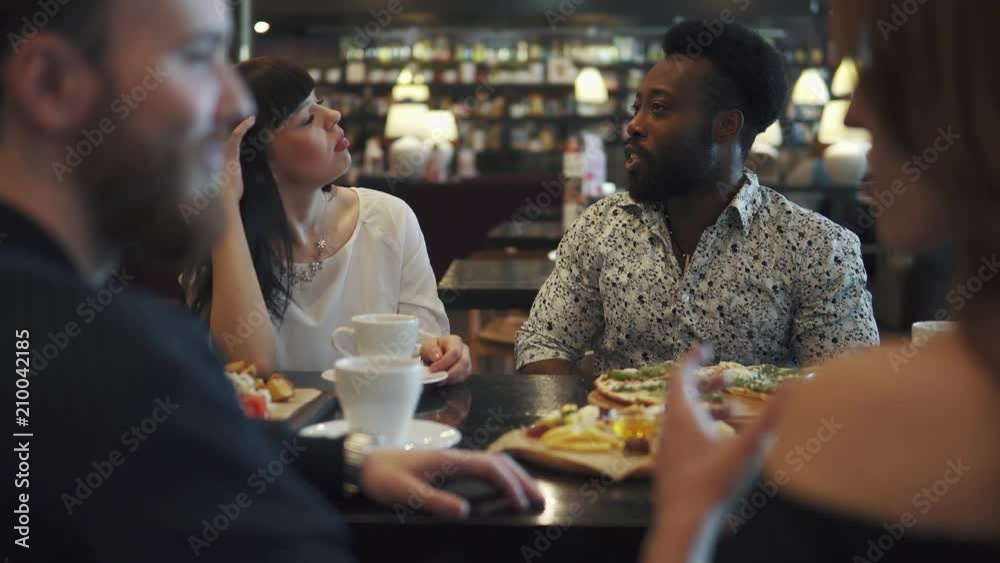 a multi-ethnic group of friends in a cafe. young black man and girl have fun talking to each other a multi-ethnic group of friends in a cafe. young black man and girl have fun talking to each other