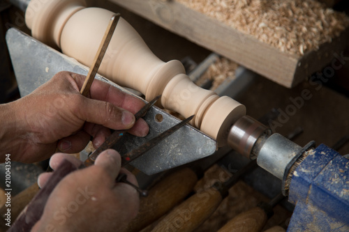 Carpenter turning hard wood on a lathe hands close up