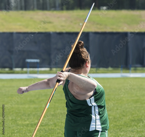 High school female throwing the javelin from behind