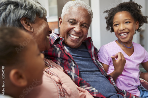 Grandparents Relaxing On Sofa At Home With Granddaughters photo