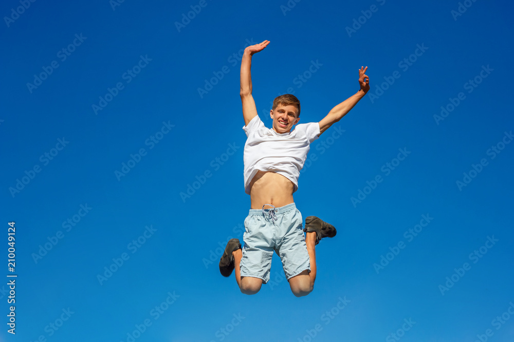 happy boy jumping in the blue sky , concept of happiness