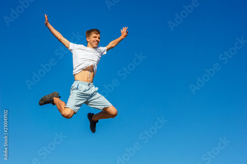 happy boy jumping in the blue sky , concept of happiness