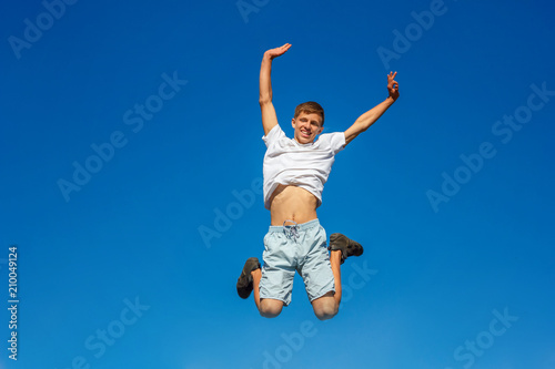 happy boy jumping in the blue sky , concept of happiness