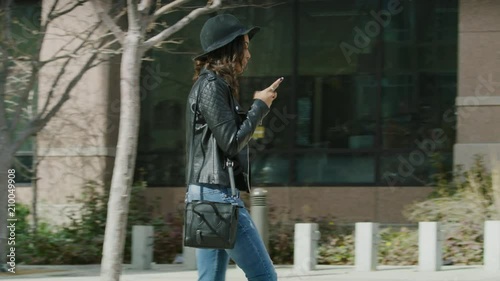 Slow motion shot of distracted woman texting on cell phone walking into post on sidewalk / Salt Lake City, Utah, United States