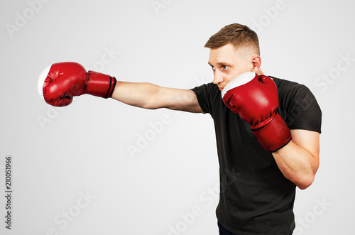 Young man in red boxing gloves on a light background. © vika33