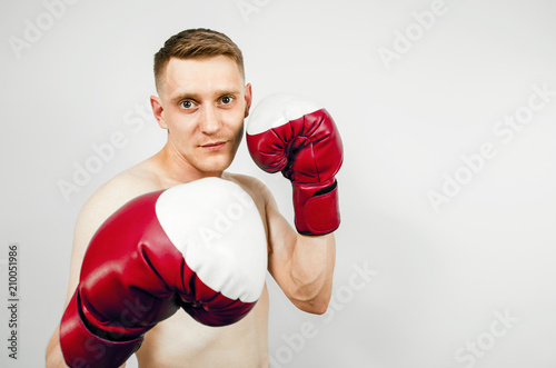 Young guy in red boxing gloves on a light background. © vika33