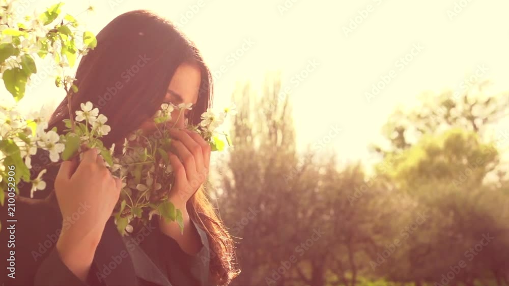 Beauty young woman enjoying nature in spring apple orchard, Happy beautiful girl in garden with blooming trees. Slow motion 4K UHD video footage. 3840X2160