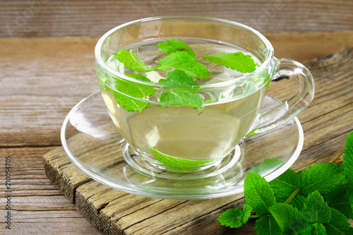 Fresh organic mint tea in glass on wooden table.