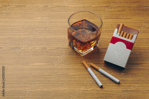 Obraz na plátně a glass of bourbon whiskey, two cigarettes with a cigarette pack on the wooden t