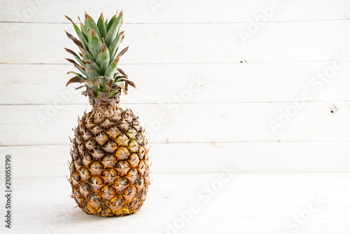 organic pineapple fruit on white painted wood, generous copy space