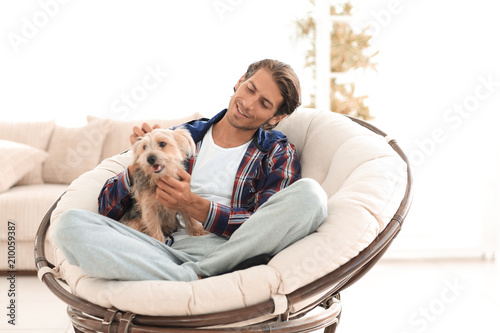 handsome guy with a dog sitting in a large armchair.